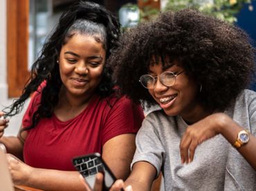 Two older teens looking at a cell phone