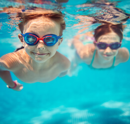 Two kids swimming together underwater wearing goggles